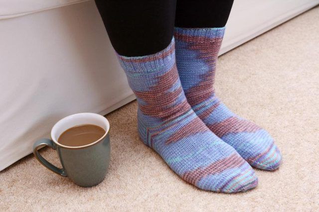 Une femme's knitted socks on a carpet.