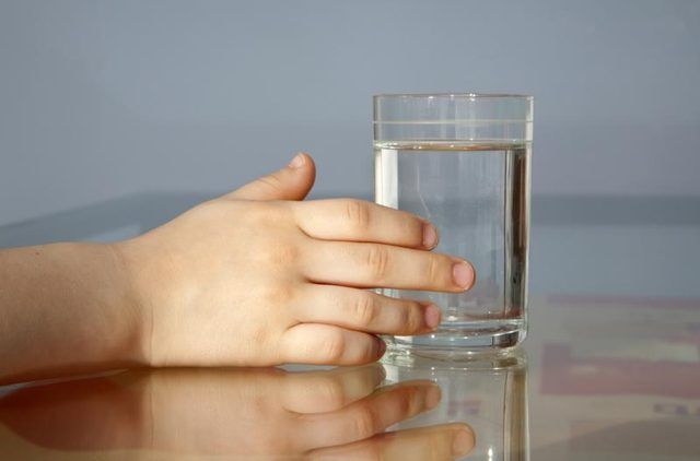 Un enfant touche un verre d'eau.
