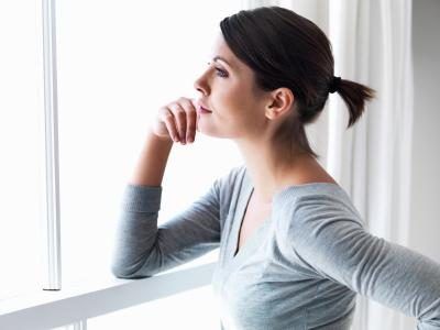 Femme regardant pensivement par la fenêtre