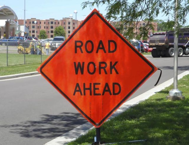 Un panneau orange avertissant les conducteurs de travaux routiers à venir.