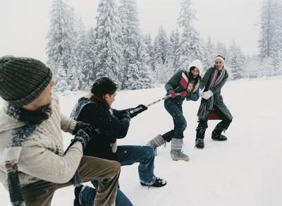 Amis jouant à un jeu de bras-de-guerre dans la neige.