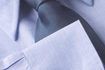 Une chemise bleu bouton-up avec une cravate qui est une nuance plus foncée ou deux est une pratique de style commun.