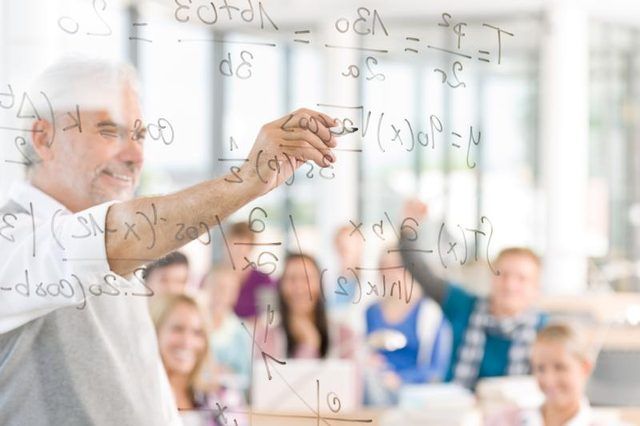Un professeur écrit des équations sur un panneau indicateur clair devant ses élèves